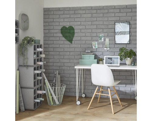 Bureau avec bureau, chaise, étagères et articles de décoration devant un mur de briques grises