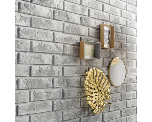 Décoration murale avec aspect pierre et éléments décoratifs tels que cadres photo, miroir et ornement de feuille