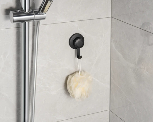 Scène de douche avec pomme de douche, barre de douche, éponge de bain et crochet à ventouse noir au mur