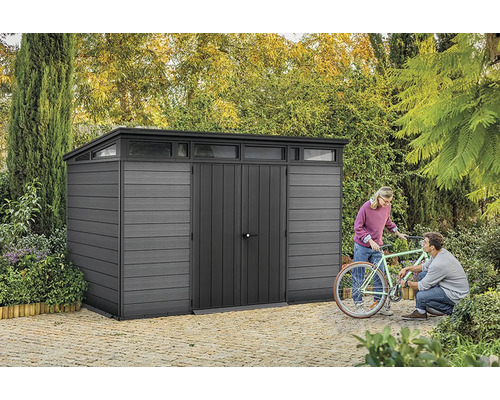 Abri de jardin gris avec lanterneau et deux personnes réparant un vélo