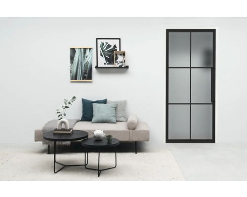 Wohnzimmer mit Sofa, Couchtischen, Wanddekoration und Innentür