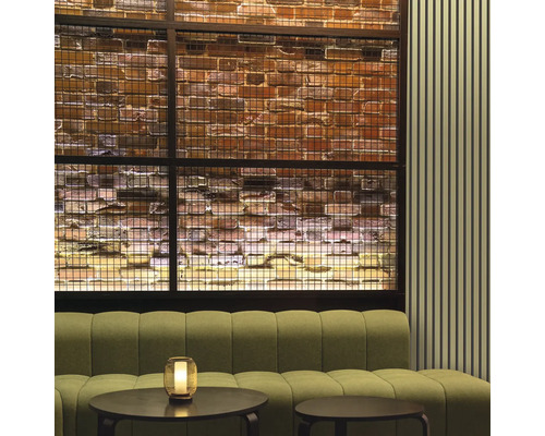 Innenraum mit Sofa, Tischen und dekorativer Ziegelwand hinter einem Metallgitter