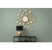 Arrangement décoratif avec miroir en forme de soleil, lampe de table et chandeliers sur une console.