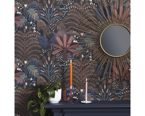 Detailaufnahme eines Raumes mit gemusterter Dschungeltapete, verziert mit Leoparden und Bäumen, zusammen mit einem Spiegel und Dekorationen auf einem Kaminsims.