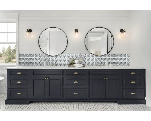 Salle de bains avec meuble sous-lavabo bleu, deux miroirs ronds et carrelage à motifs