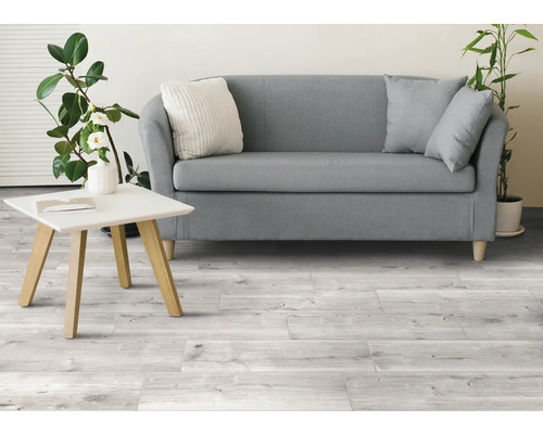 Salon lumineux avec canapé, table et carrelage imitation bois.