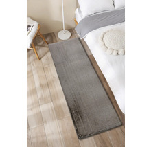 Tapis gris à côté d''un lit sur un plancher en bois