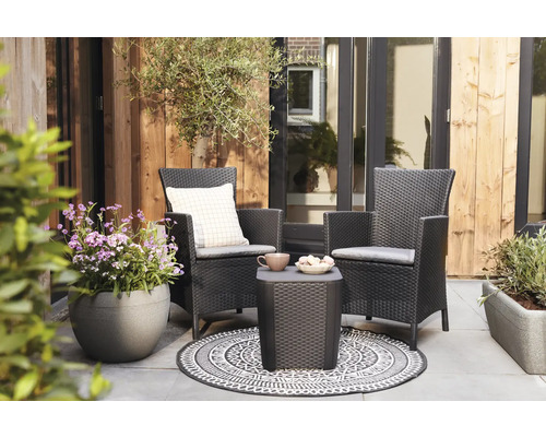 Terrasse avec deux fauteuils en rotin, une table d''appoint, un tapis et des plantes