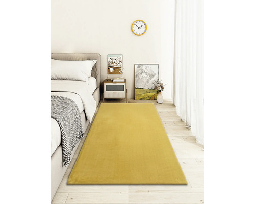 Tapis jaune dans la chambre à coucher, à côté d''un lit et d''une table de chevet.