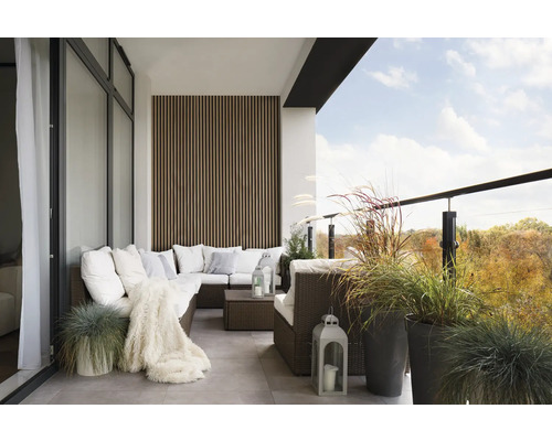 Balcon avec canapé en rotin, coussins, couverture, lanternes et plantes en pot