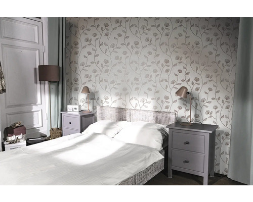 Schlafzimmer mit Bett, Nachttischen und floraler Tapete