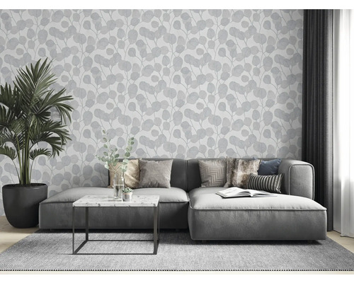 Salon avec canapé gris, plante d''intérieur et papier peint à motif de feuilles