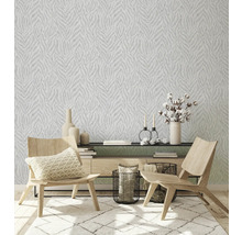 Wohnzimmer mit gemusterter Tapete, Teppich und Holzmöbeln.
