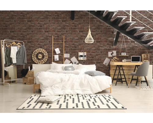 Chambre avec lit, bureau et escalier devant un mur de briques