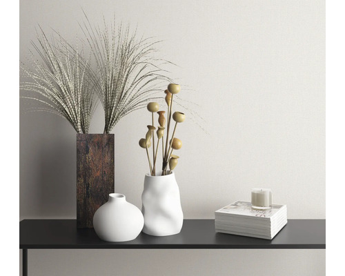 Scène décorative avec vases, fleurs séchées, bougie et livre sur une console