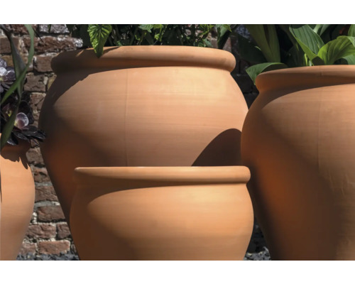 Pots de fleurs en terre cuite de différentes tailles devant un mur de briques