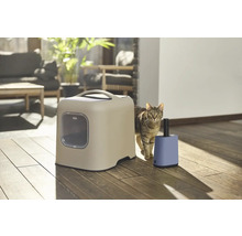 Katze neben Katzentoilette und Lufterfrischer in einem hellen Raum.