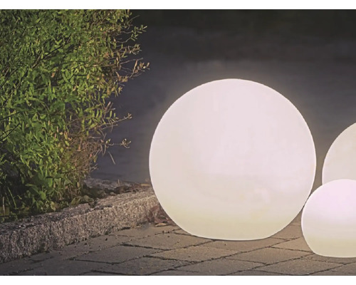Beleuchtete Kugeln für den Aussenbereich auf Pflastersteinen neben einer Hecke