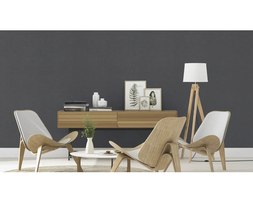 Helles Wohnzimmer mit Holzmöbeln, Stehlampe und Dekorationsartikeln vor einer grauen Wand