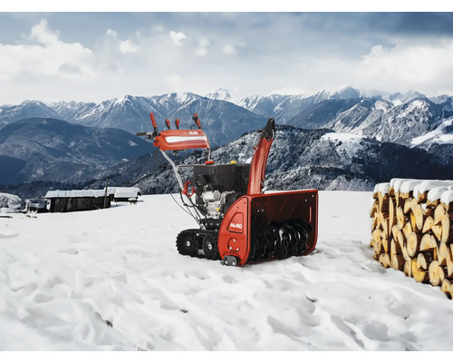 Fraise à neige AL-KO en action devant un paysage de montagne enneigé