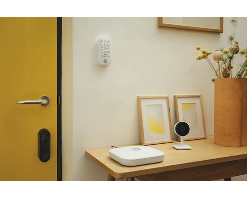 Scène avec un système de sécurité, comprenant un clavier, une station de base, une caméra et une serrure de porte intelligente
