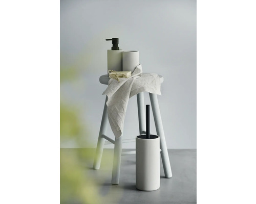 Badezimmer-Accessoires auf einem Hocker: Seifenspender, Becher, Seife, Handtuch und WC-Bürste