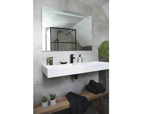 Salle de bains avec lavabo, miroir, serviettes et décoration sur un banc en bois.