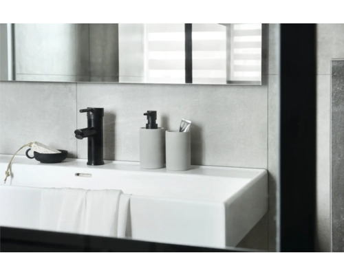 Lavabo avec robinet, distributeur de savon et gobelet à brosses à dents dans la salle de bains.