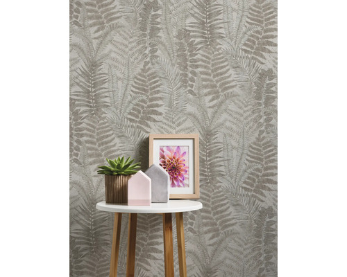 Pièce avec papier peint à motif de fougère, table d''appoint, plante d''intérieur et cadre photo