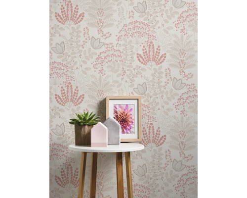Intérieur décoratif avec papier peint à fleurs, table, plante en pot et cadre photo.