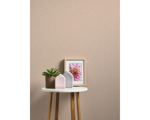 Nature morte décorative avec une plante, deux maisons décoratives et une image encadrée sur une petite table devant un mur uni