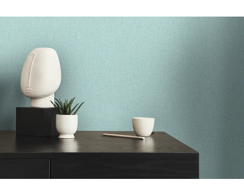 Papier peint intissé clair et structuré sur un mur à côté d''une commode avec des décorations.