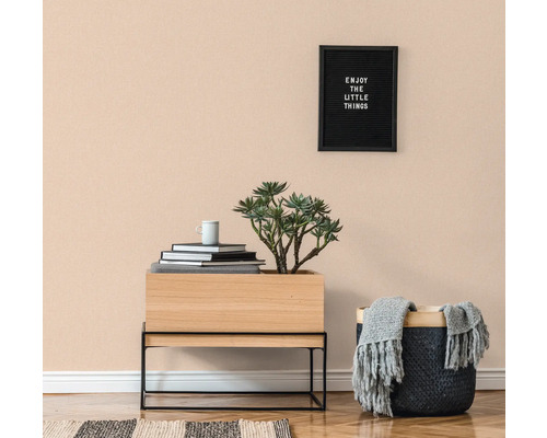 Pièce lumineuse avec parquet, commode, plante en pot, panier et décoration murale