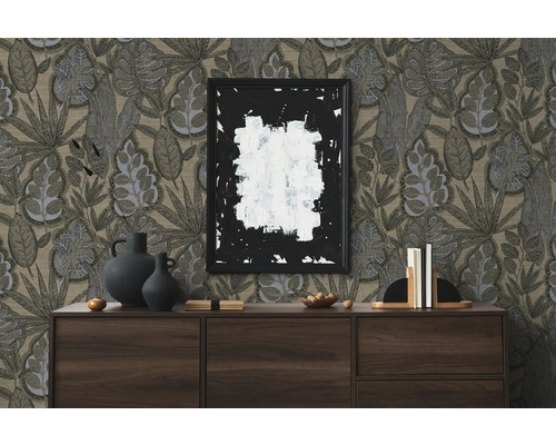 Wohnszene mit Kommode, Dekorationsobjekten, einem gerahmten Bild und einer Tapete mit Blattmuster