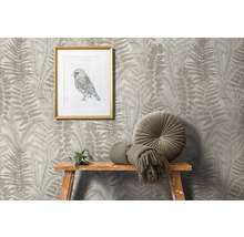Scène avec papier peint à motif de fougère, image d''oiseau encadrée, coussin rond et décoration sur un tabouret en bois