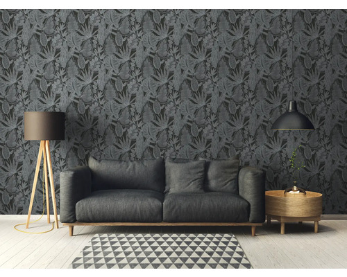 Salon avec canapé devant un papier peint foncé à motif de feuilles