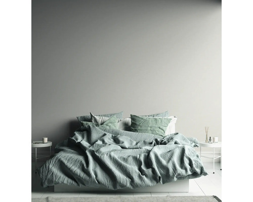 Chambre claire avec lit, tables de chevet et éléments décoratifs.