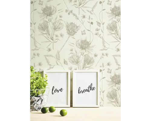 Scène avec papier peint fleuri, deux affiches encadrées avec les inscriptions amour et respirer, plante en pot et citrons verts