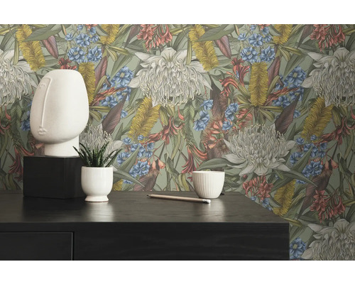 Dekoratives Interieur mit Blumentapete, Gesichtsskulptur und Pflanze im Topf auf einem dunklen Tisch.