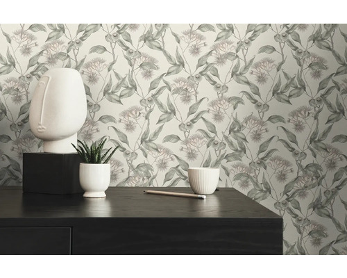 Scène avec une commode, une sculpture de visage blanche et un papier peint à motif floral.