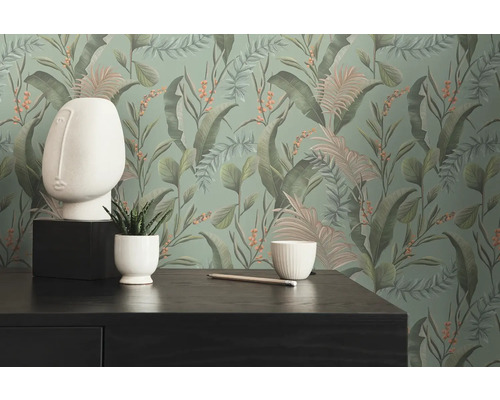 Dekorative Tapete mit Pflanzenmotiven im Interieur mit Tisch, Bleistift und Dekoration