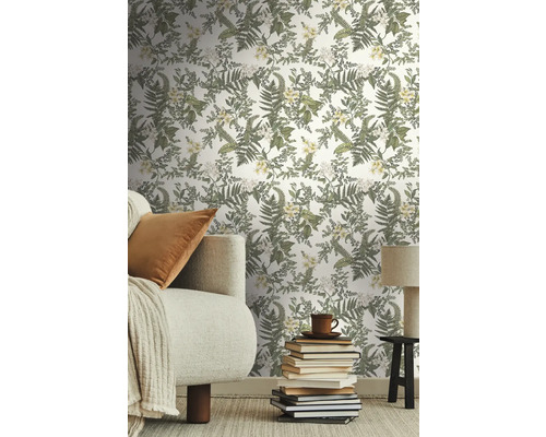 Salon avec papier peint à motifs floraux, canapé, livres et lampe