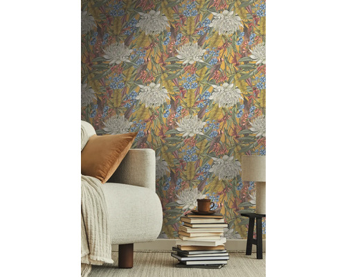 Salon avec papier peint intissé floral, canapé et pile de livres.