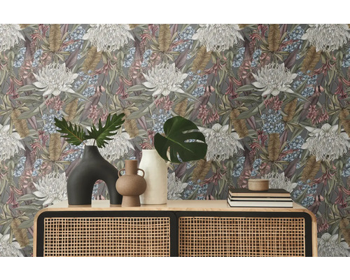 Raumansicht mit floral gemusterter Tapete, Kommode mit Rattangeflecht und Dekorationsgegenständen