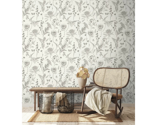 Pièce décorative avec papier peint à motifs d''oiseaux, de fleurs et de papillons, un tapis, un banc, des paniers et un fauteuil à bascule.