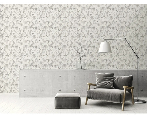 Vue d''une pièce avec un papier peint à motif floral, un fauteuil, un lampadaire et une table basse.