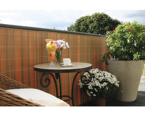Szene mit einem Tisch, einem Eisbecher, Blumen, einer Tasse Kaffee und einem Sichtschutzzaun