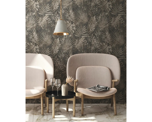 Salon avec papier peint à motifs de feuilles, deux fauteuils, une table d''appoint, une lampe et des objets de décoration.