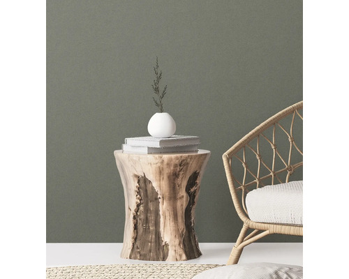 Dekorative Szene mit einem Holzhocker, Büchern, einer Vase und einem Korbsessel für ein stilvolles Ambiente.