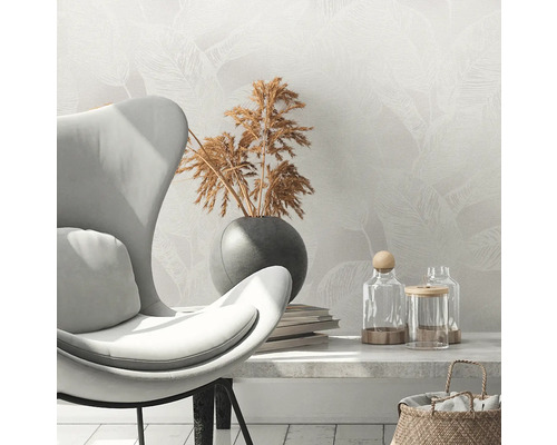 Szene mit Sessel, Trockenblumen in Vase, Büchern und Dekogläsern